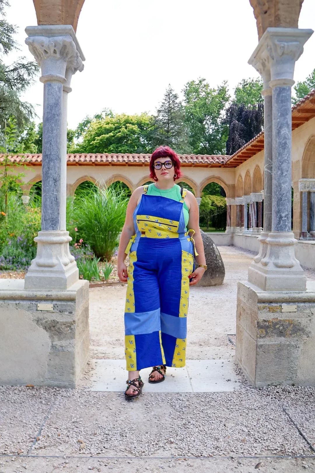 Femme portant la salopette patchwork bleu et jaune à citrons sous des arcades en pierre