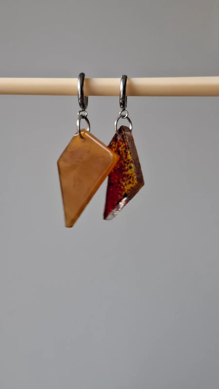 Boucles d'oreilles géométriques suspendues, une pièce jaune ambrée et une pièce rouge mouchetée de jaune.