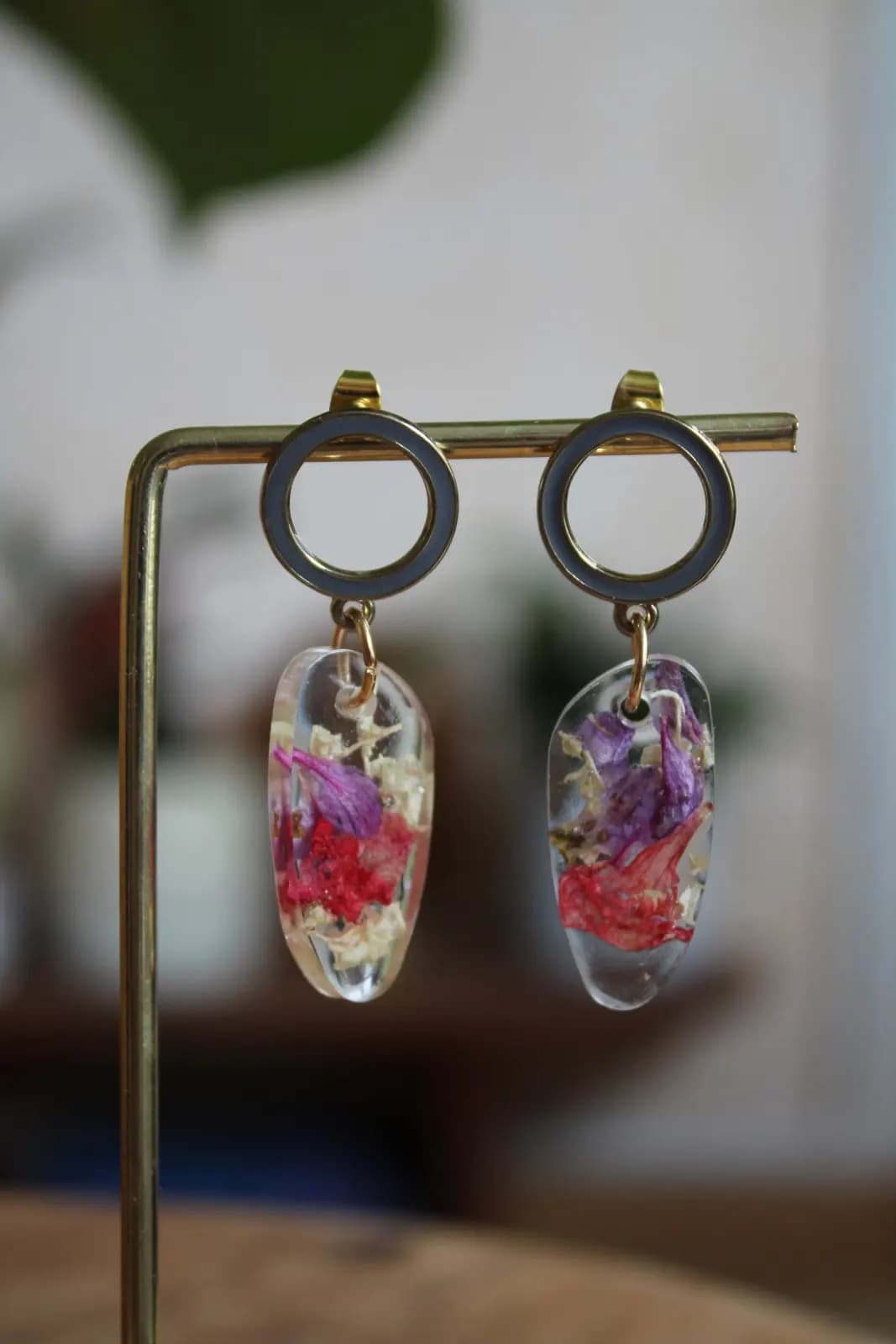 Boucles d'oreilles suspendues à anneaux dorés et gris avec pendentifs en résine et pétales violets et rouges.