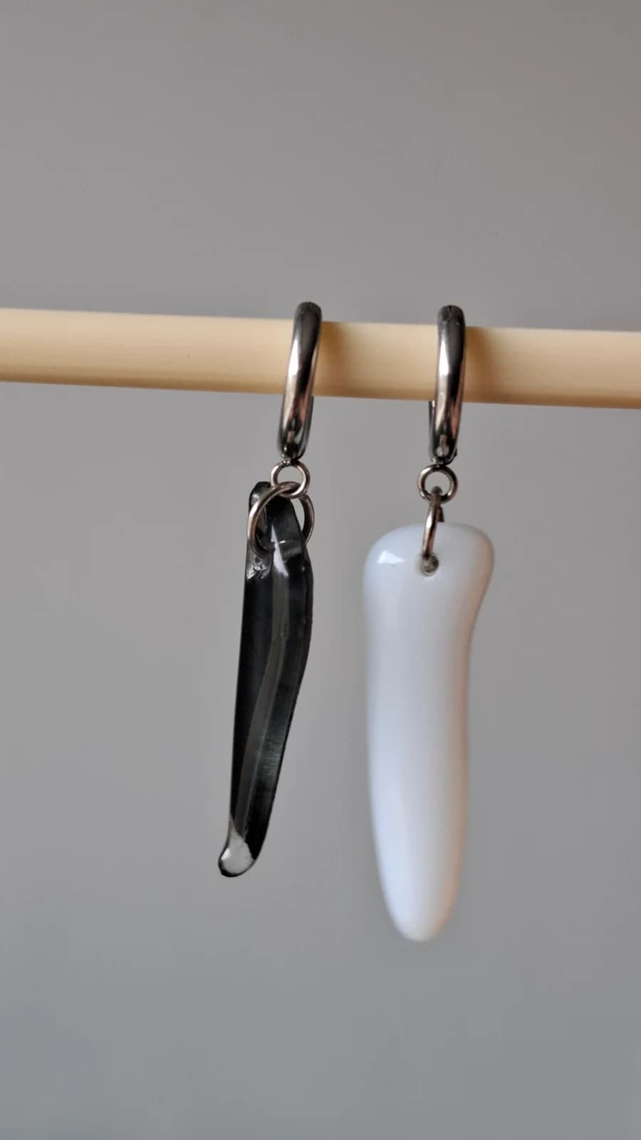 Dormeuses en acier suspendues avec un pendentif allongé noir et un blanc aux bords arrondis.