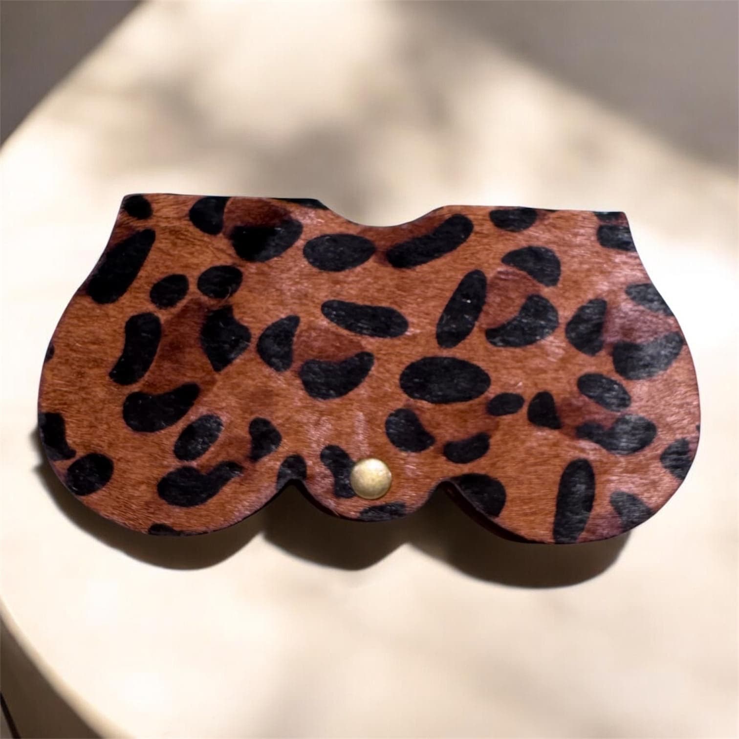 Étui à lunettes galbé forme papillon à motif léopard fauve et noir fermé par un bouton pression