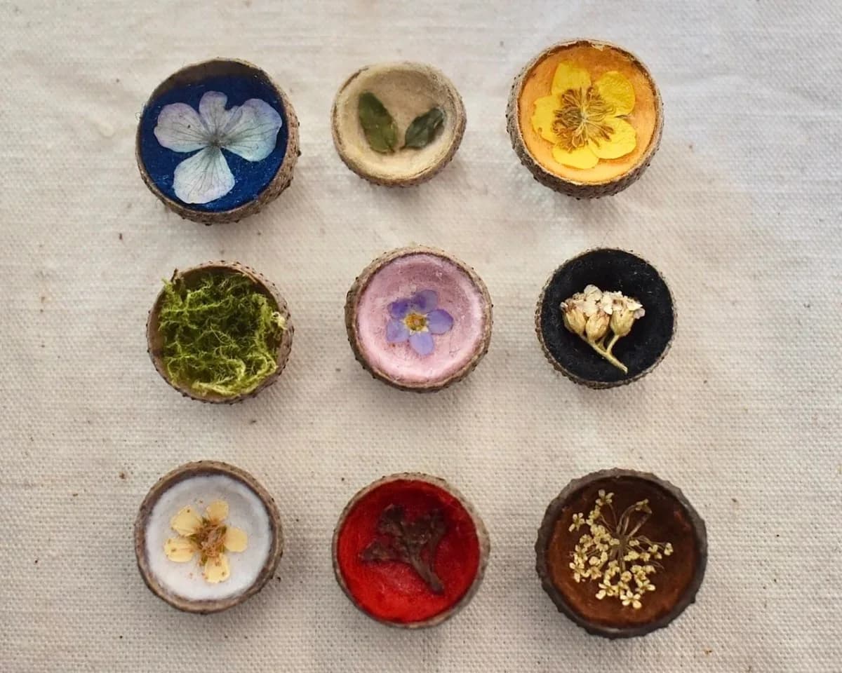 Gros plan sur un magnet artisanal en cupule de gland orné d'une petite fleur pressée