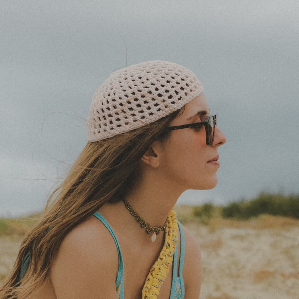 Profil d'une femme portant le bonnet ajouré beige en extérieur