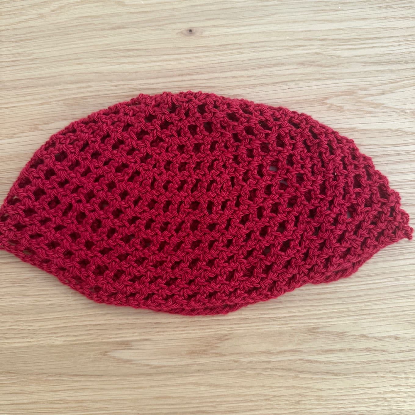 Femme portant le bonnet ajouré en maille rouge vif tenant un manche en bois