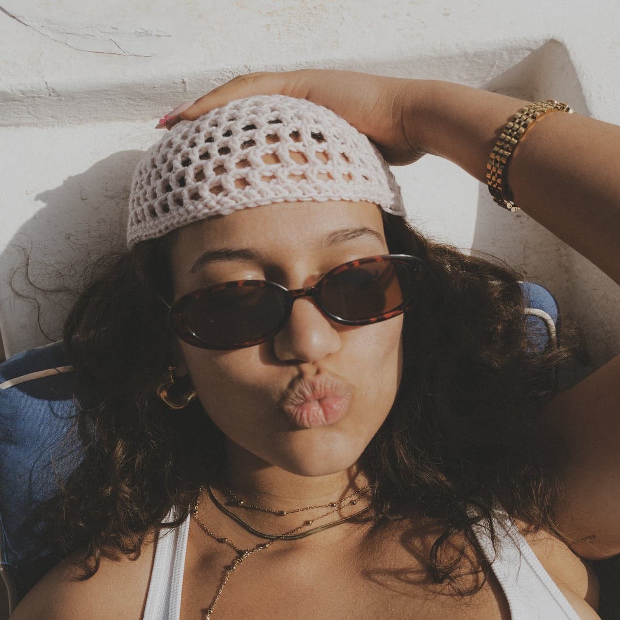 Femme portant le bonnet ajouré en maille rose clair avec des lunettes de soleil
