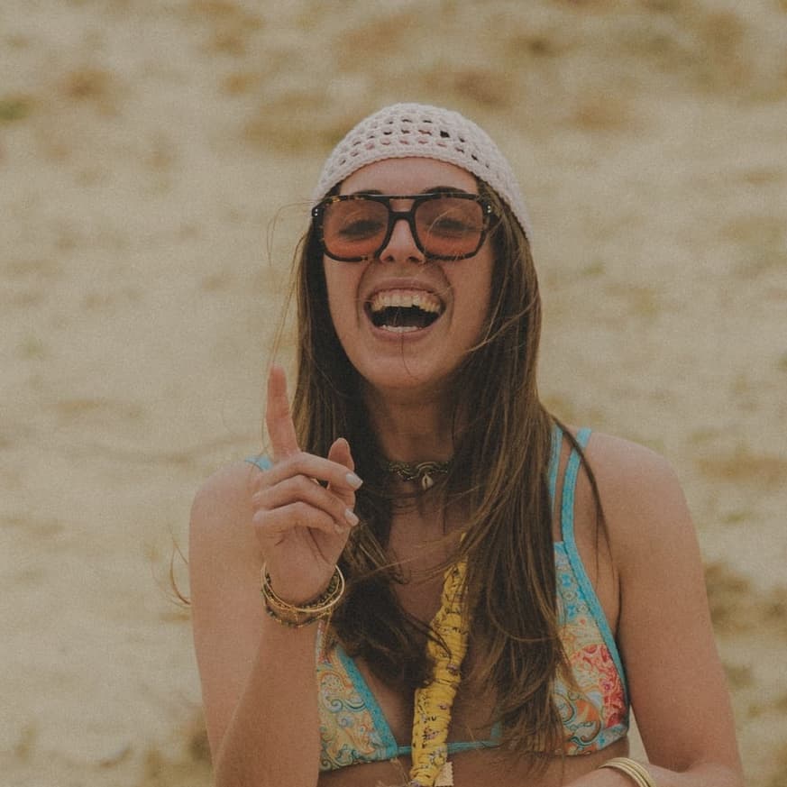 Femme souriante portant un bonnet ajouré en maille claire et des lunettes de soleil en extérieur