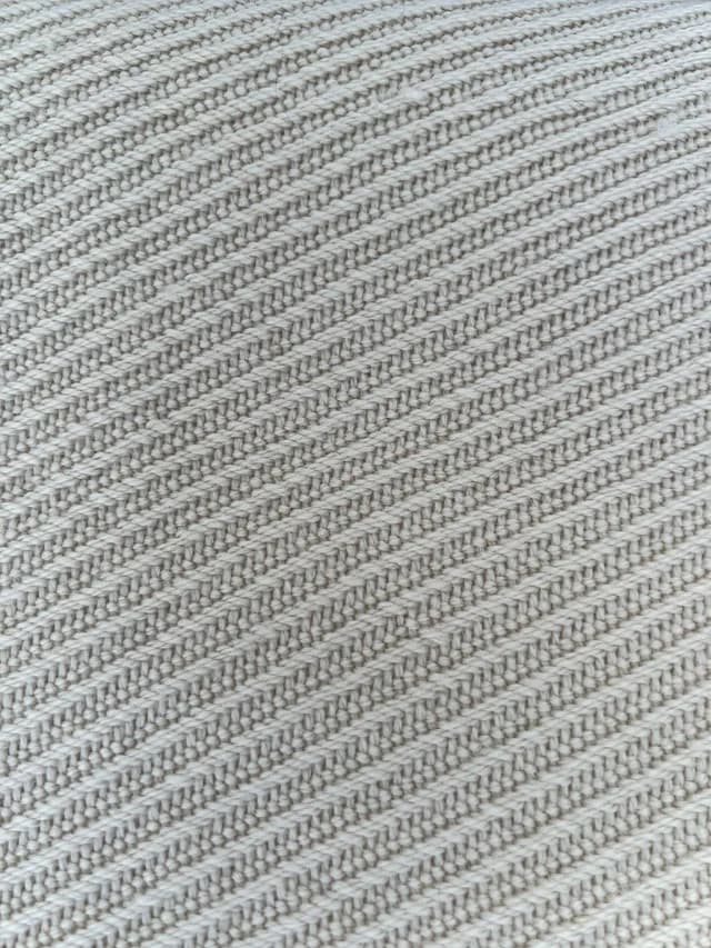Détail du tissage artisanal et des franges nouées de l'écharpe en laine couleur champagne.