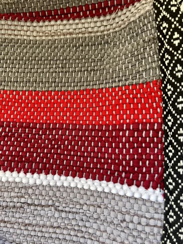 Gros plan sur le tissage artisanal et la bordure graphique du plaid pour canapé