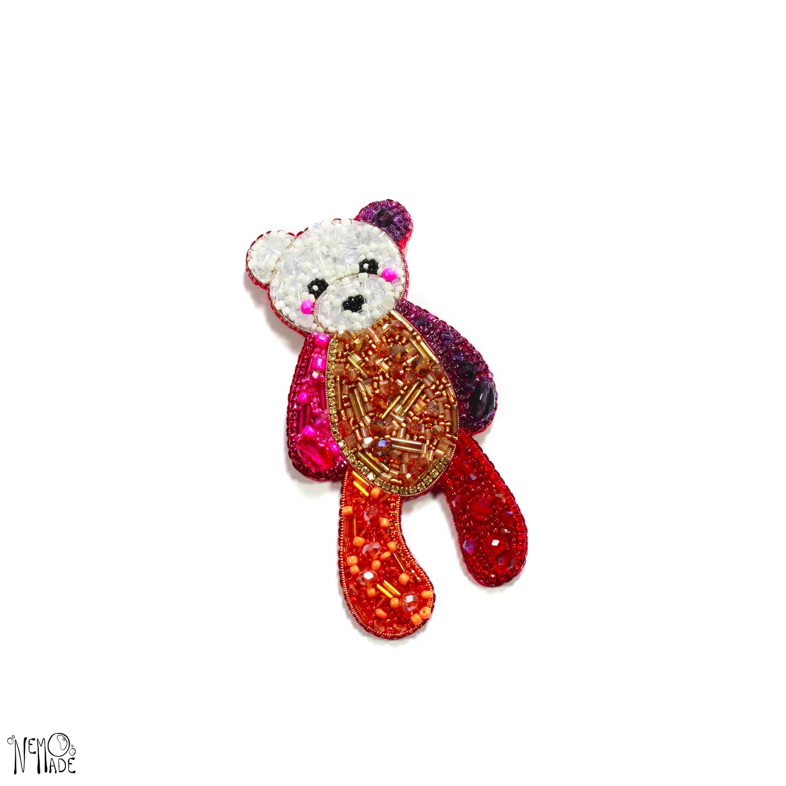 Broche ourson brodée de perles et sequins aux nuances de rouge, rose et orange sur fond blanc.