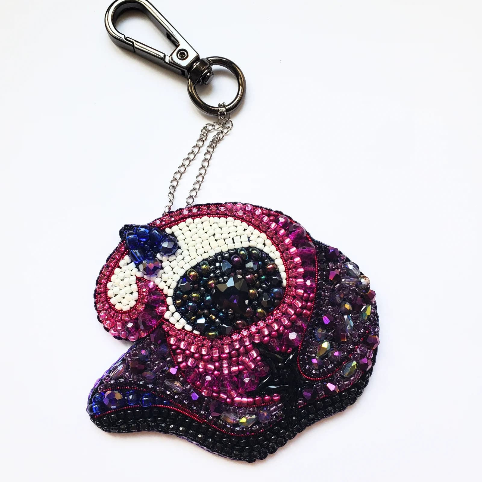 Porte-clé brodé Dimitri en perles et sequins violets, roses et noirs avec mousqueton sur fond blanc.