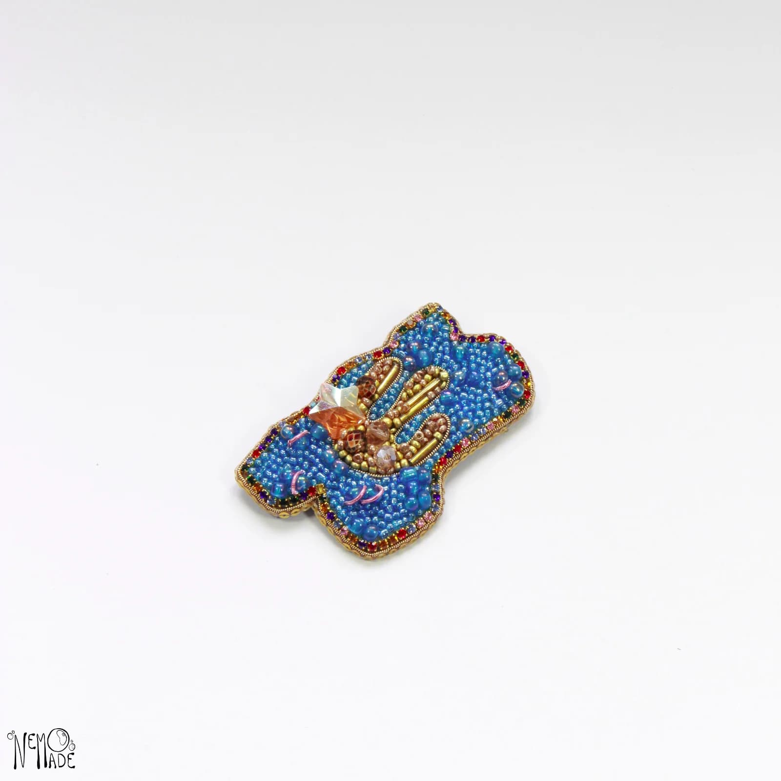 Broche artisanale Stardust brodée de perles bleues et dorées ornée d'un détail étoilé.