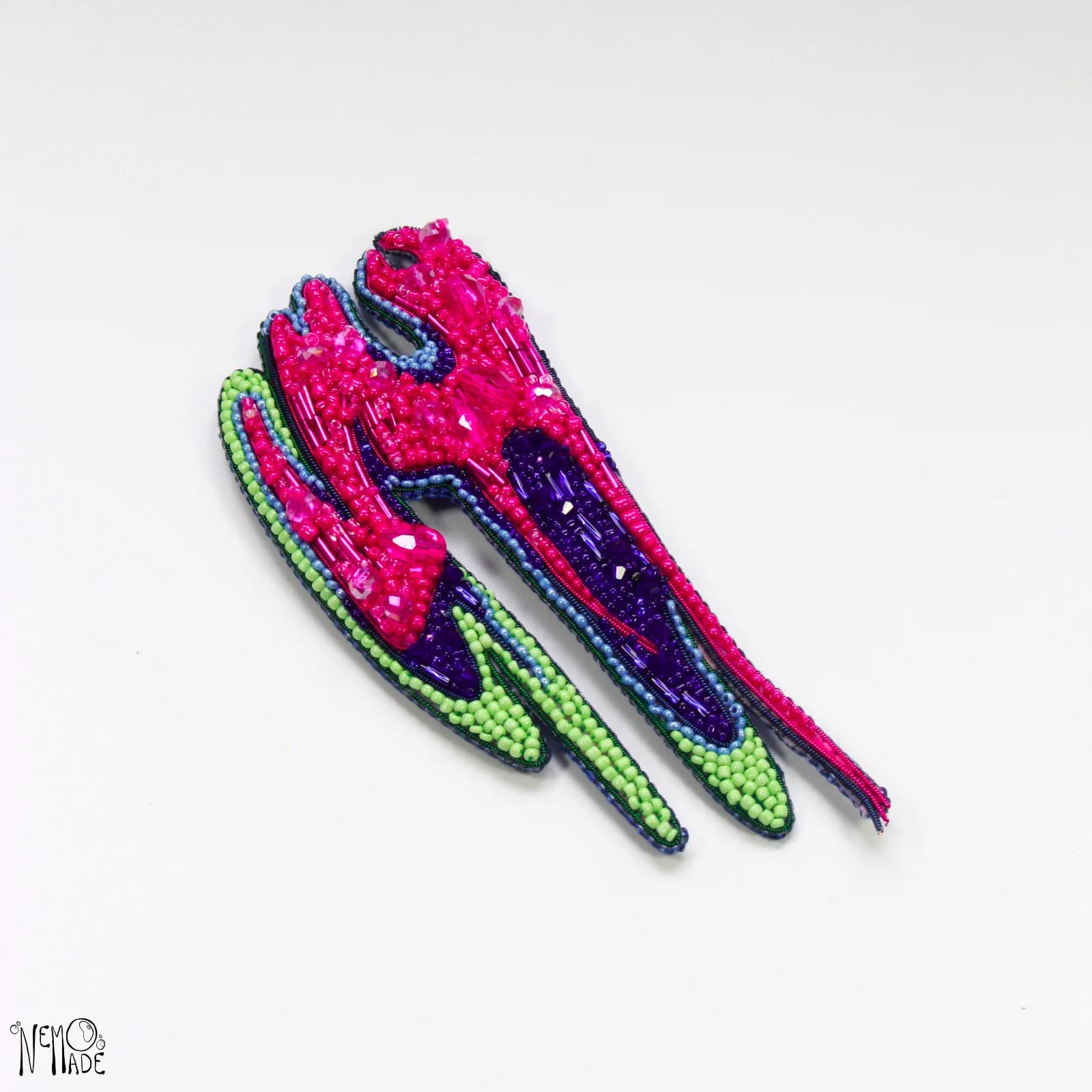 Broche RCKSTR brodée main de perles fuchsia, violettes et vertes sur fond blanc