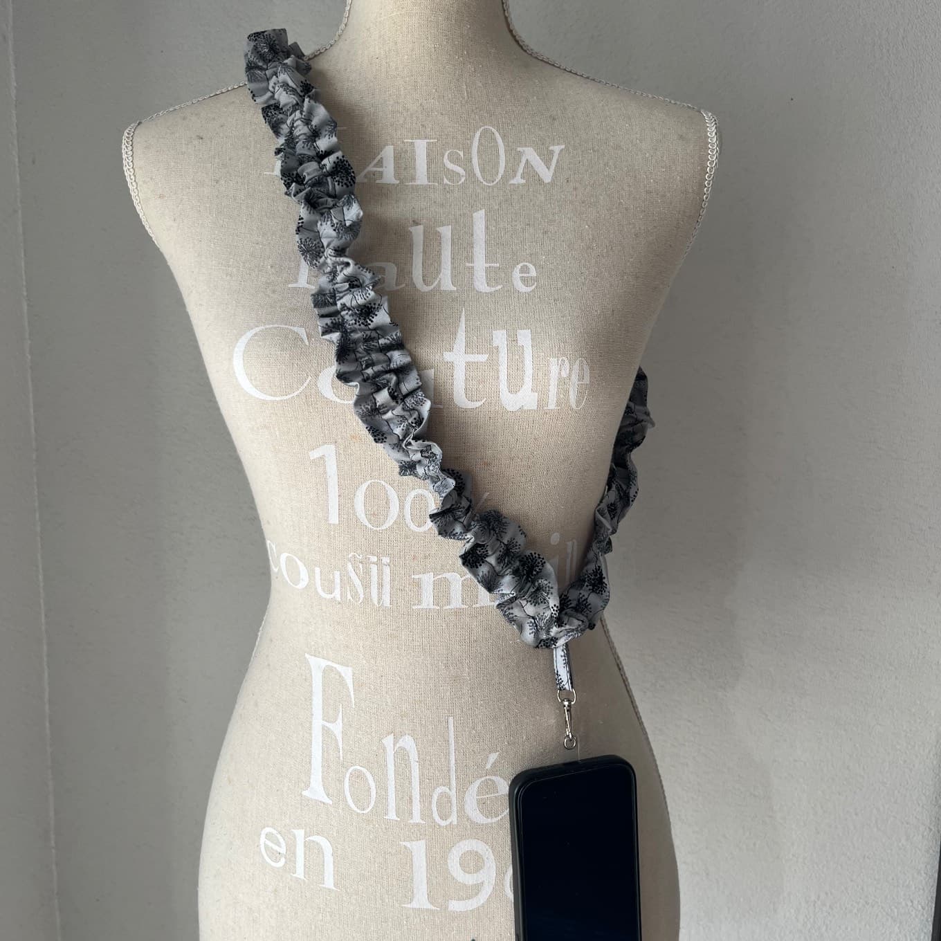 Bandoulière de téléphone froncée en tissu gris à motifs pissenlits