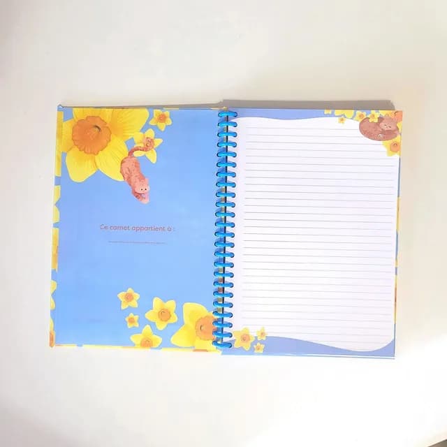 Couverture cartonnée du carnet A5 avec motif de chat roux et fleurs jaunes.