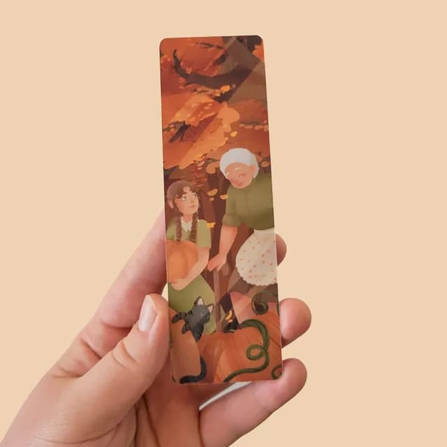 Marque-page tenu en main illustrant une grand-mère, une jeune fille et des citrouilles en automne.