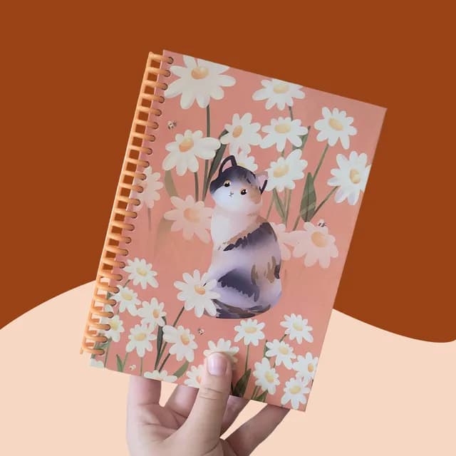 Carnet A5 à spirale orange, couverture illustrée d'un chat tricolore parmi des marguerites.