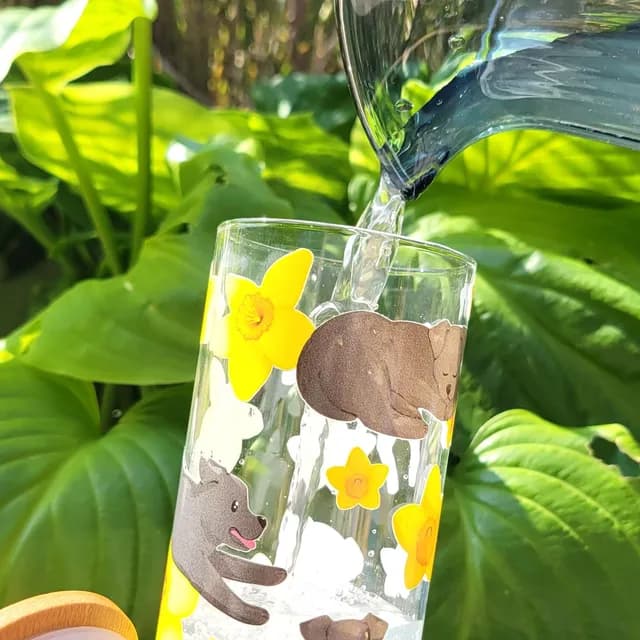 Verre cylindrique orné d'illustrations de labrador noir et de fleurs jaunes, couvercle en bambou et paille.