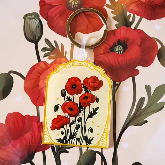 Porte-clés rectangulaire arrondi avec illustration de coquelicots rouges sur fond jaune clair et bordure dorée