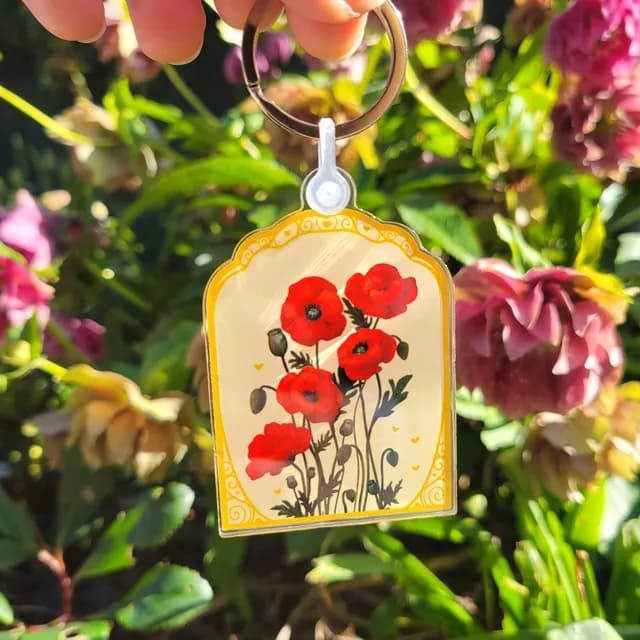 Vue rapprochée du porte-clés illustré de coquelicots rouges aux tiges vertes et boutons floraux