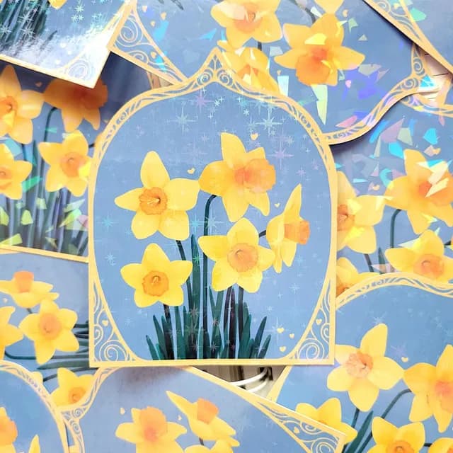 Autocollant illustré de jonquilles jaunes sur fond bleu révélant ses finitions irisées