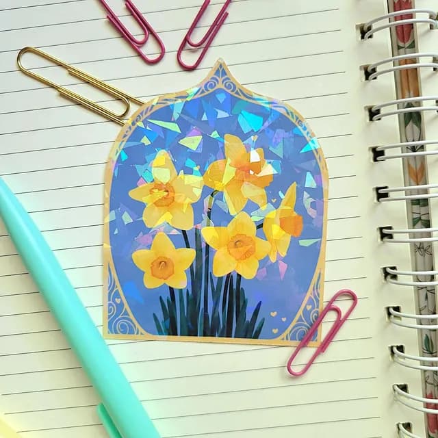 Sticker en forme d'arche avec des jonquilles jaunes et reflets holographiques posé sur un carnet