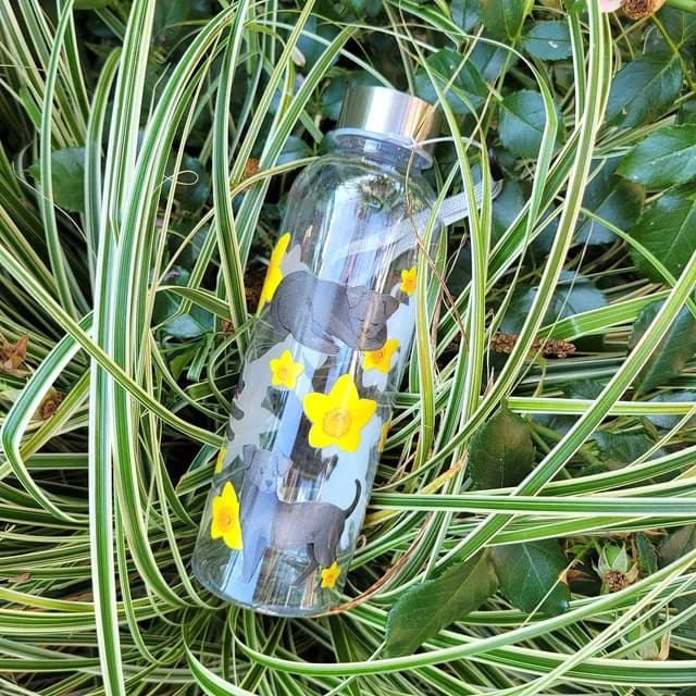 Vue rapprochée des motifs de chiots labrador noir et fleurs jaunes sur la bouteille transparente.
