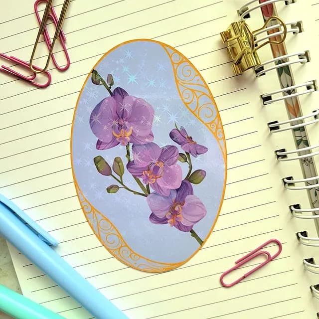 Sticker ovale aux orchidées violettes avec reflets holographiques étoilés, posé sur un carnet à spirale.