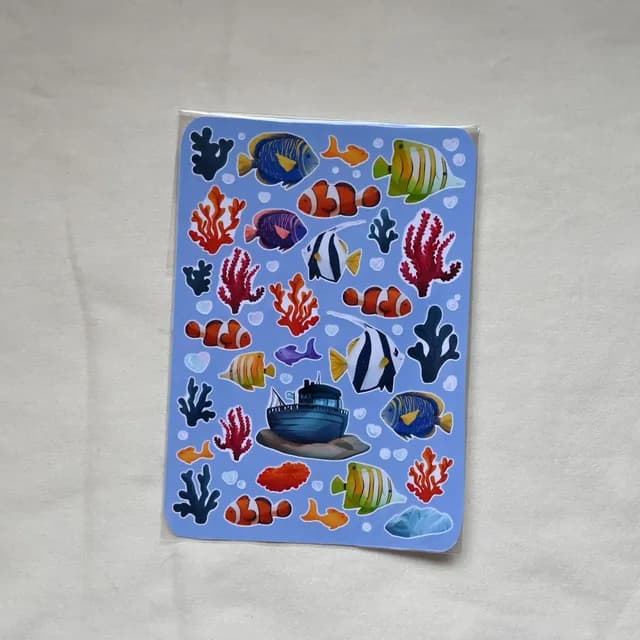 Planche complète d'autocollants marins illustrés de poissons colorés et algues sur fond bleu clair.