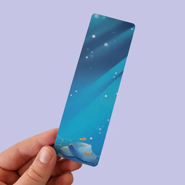 Marque-page tenu en main, illustré d'un décor sous-marin bleu avec petits poissons et rochers.