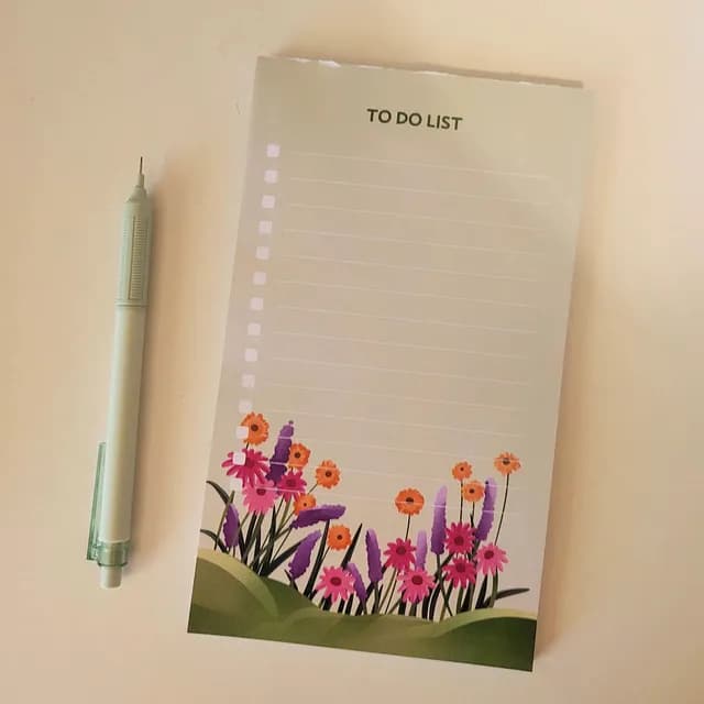 Bloc-notes to-do list ligné illustré de fleurs colorées en bas de page, à côté d'un porte-mine.