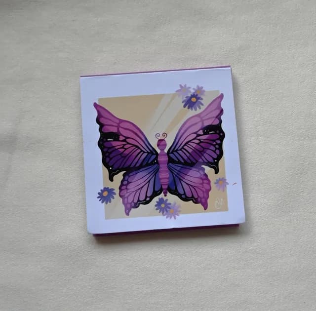 Bloc-notes carré avec couverture illustrée d'un papillon violet et de fleurs sur fond clair