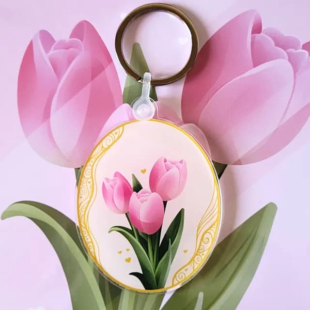 Porte-clés ovale illustré de trois tulipes roses avec bordure dorée, posé sur fond floral assorti.