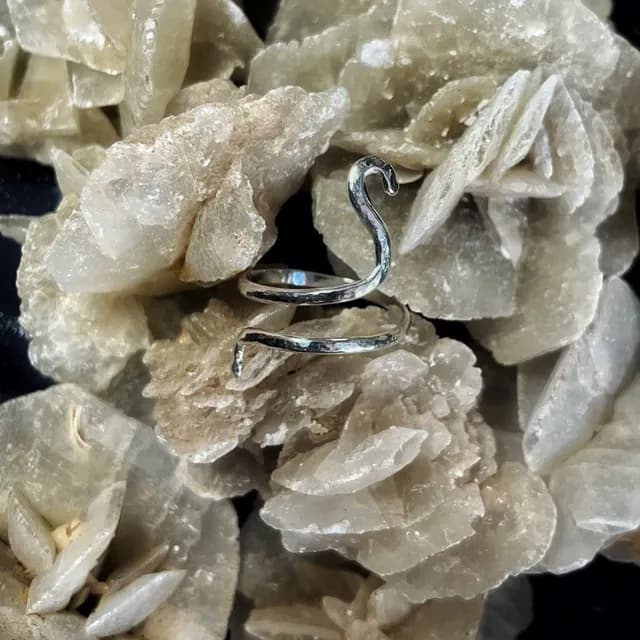 Bague de phalange réglable en spirale argentée posée sur une pierre minérale