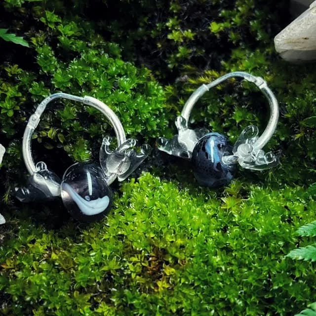 Créoles en argent ornées de perles en verre sombres et transparentes, posées sur de la mousse végétale
