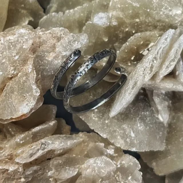 Bague de phalange en argent 925 en spirale ciselée, posée sur une roche minérale claire.
