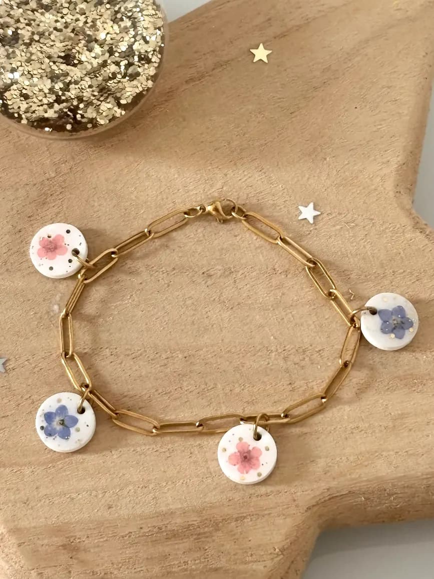 Bracelet chaîne dorée avec quatre médaillons blancs ornés de fleurs de myosotis bleues et roses