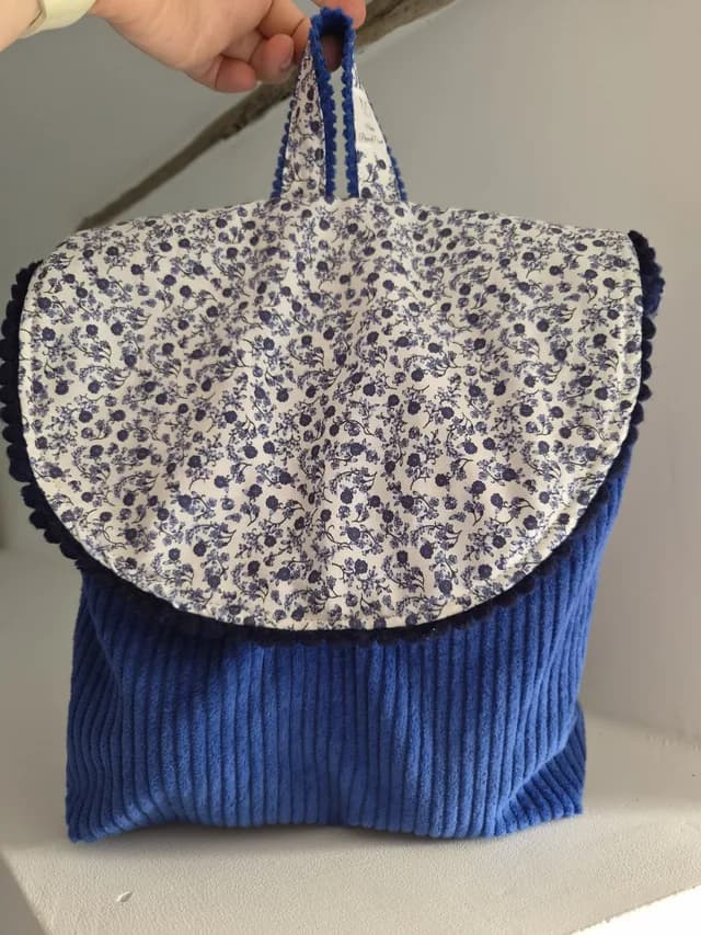 Sac à dos enfant en velours côtelé bleu avec rabat à motifs floraux et galon à pompons