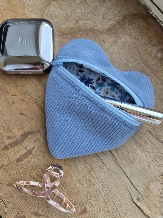 Pochette en forme de cœur en velours côtelé bleu ciel avec sa fermeture zippée assortie.