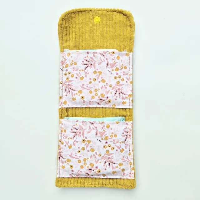 Pochette dépliée en velours moutarde avec compartiments intérieurs fleuris garnis de protections