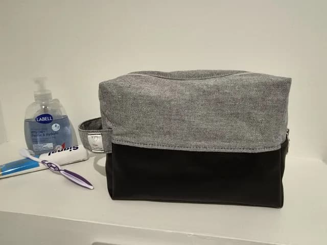 Trousse de toilette fermée en tissu gris et simili cuir noir avec poignée latérale