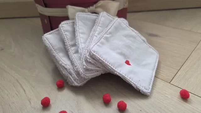 Cotons lavables carrés blancs brodés d'un petit cœur rouge disposés en éventail