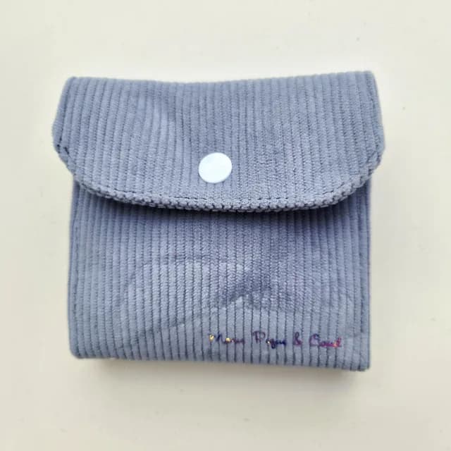 Pochette carrée fermée en velours côtelé bleu ciel avec rabat et bouton pression.