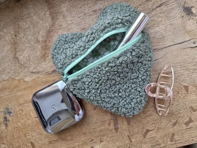 Pochette coeur en sherpa kaki ouverte révélant sa doublure fleurie avec maquillage