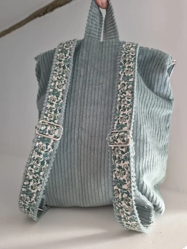 Petit sac à dos vert d'eau et imprimé fleuri posé de face.