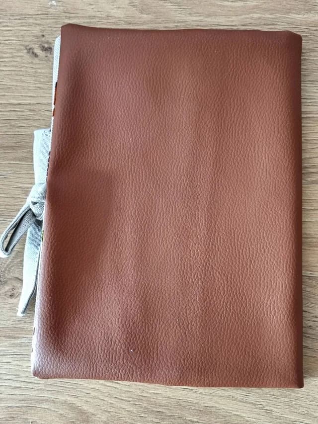 Vue rapprochée des motifs de la forêt et des finitions du protège-carnet de santé.
