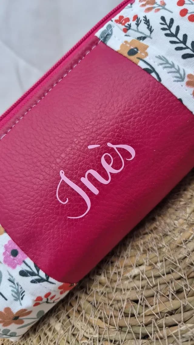 Trousse en simili-cuir rose fuchsia et tissu fleuri sur un support tressé