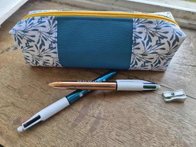 Vue d'ensemble de la trousse bleu canard avec tissu à motif feuillage et fermeture jaune.