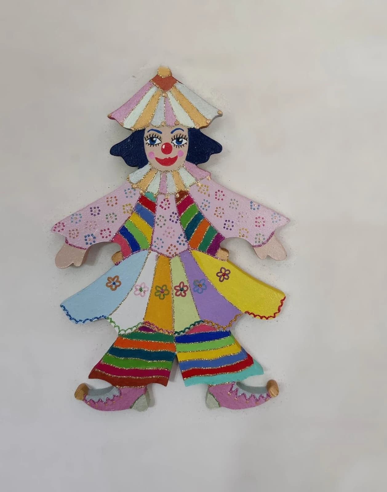 Figurine murale en bois peinte représentant le clown Zanzibelle au costume multicolore à motifs.