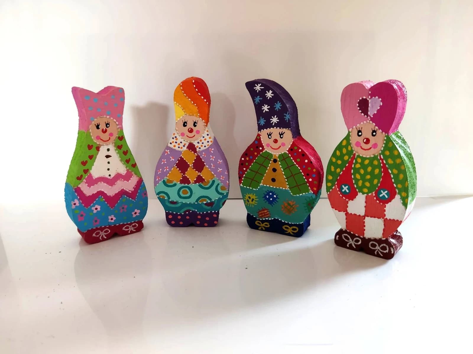 Quatre figurines Farfs en bois peintes de motifs multicolores alignées de face
