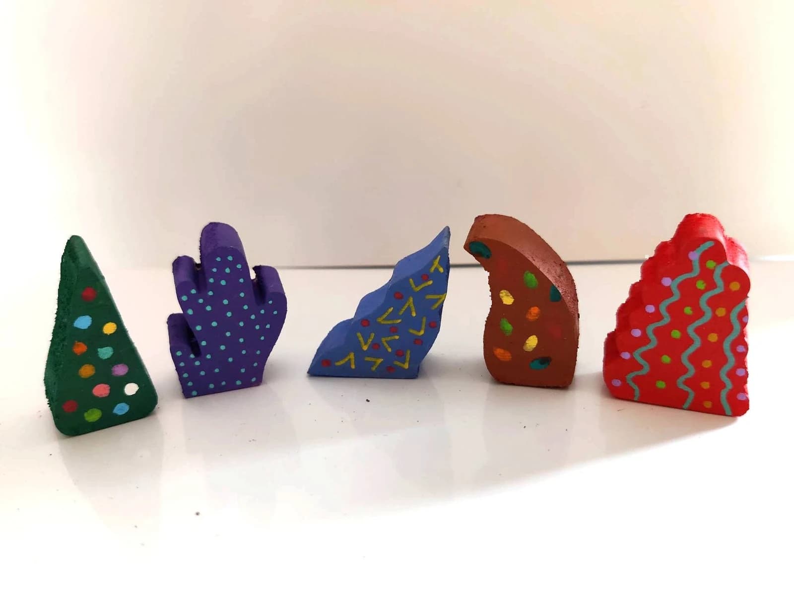 Cinq petits arbres miniatures en bois aux formes variées peints de couleurs vives et de motifs